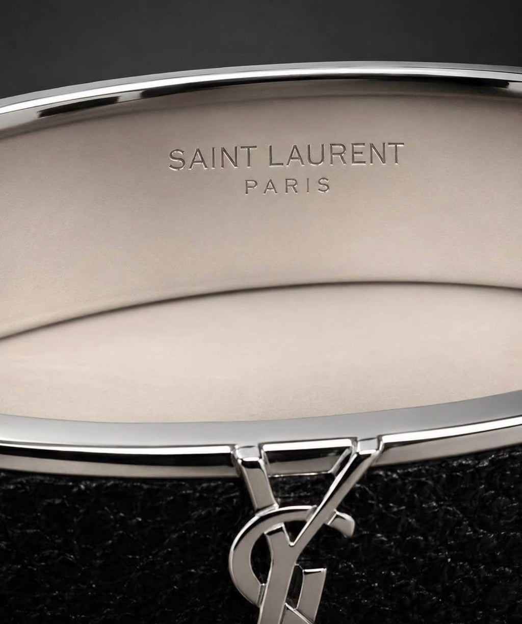 Saint Laurent Paris engraving and YSL logo detail on black leather cuff bracelet