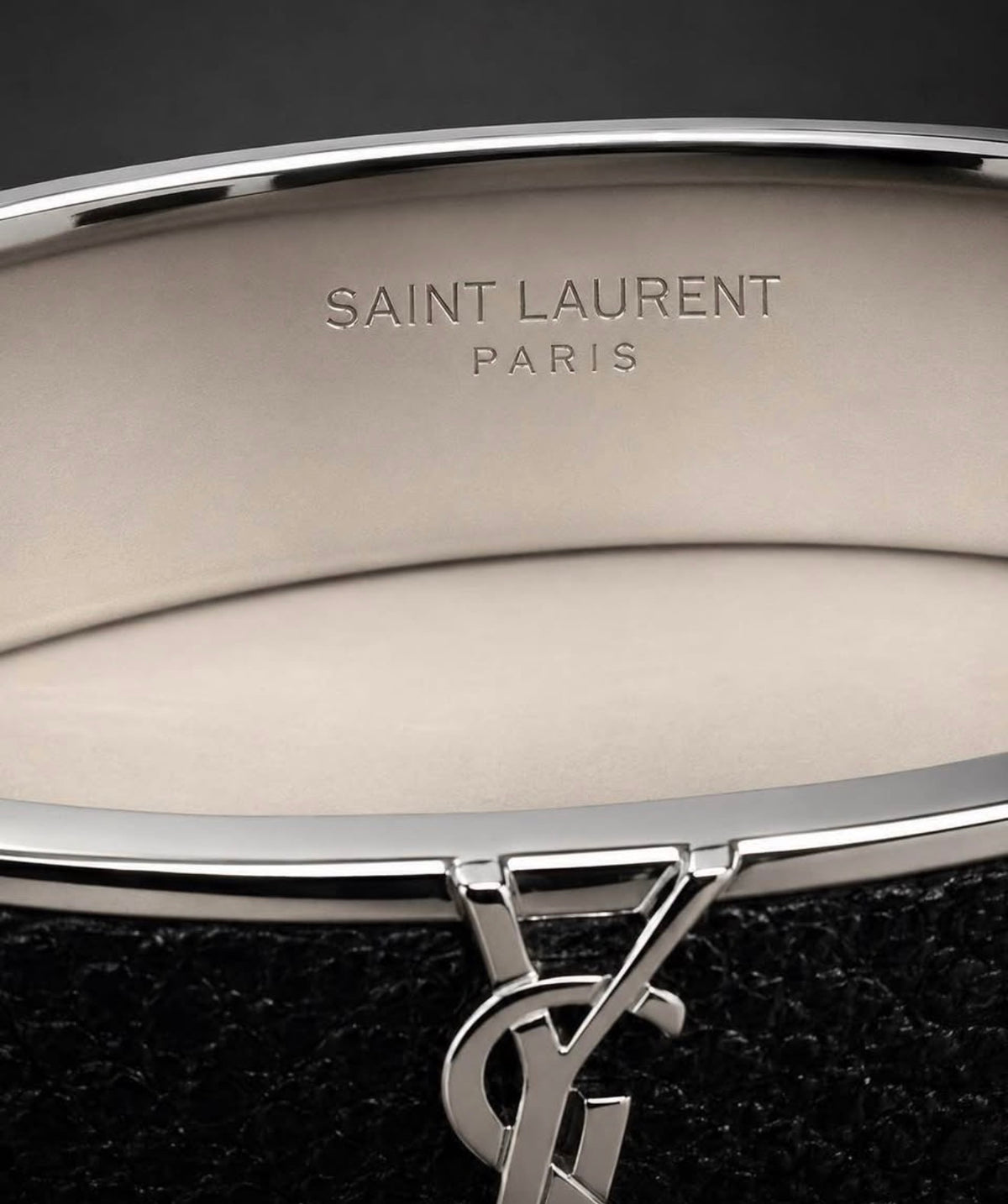 Saint Laurent Paris engraving and YSL logo detail on black leather cuff bracelet